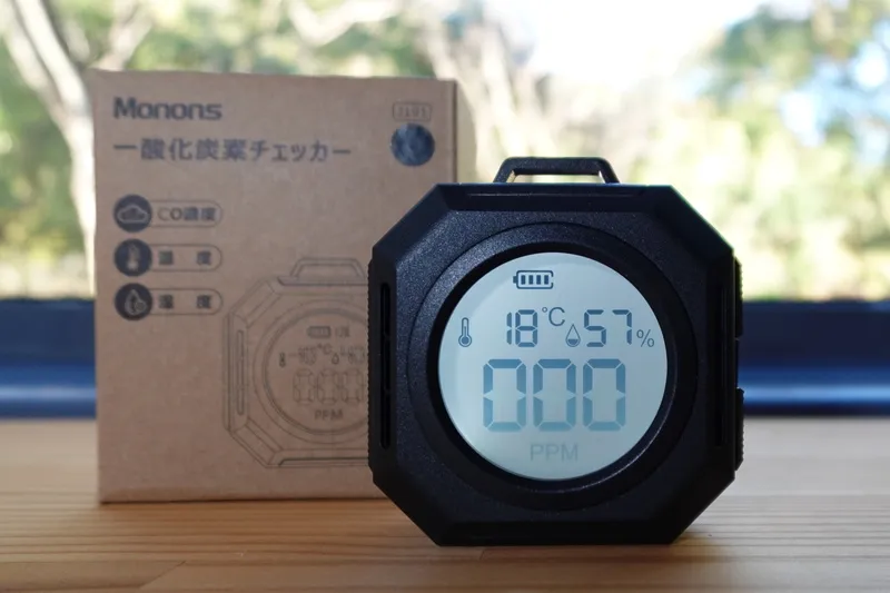モノンズ（Monons）一酸化炭素チェッカーの液晶画面と、背後に置かれた収納箱が写っている製品写真