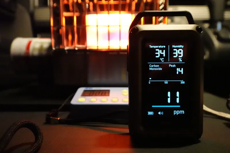 エレコム NESTOUT 一酸化炭素アラーム 3in1をカセットガスストーブの前に設置し、液晶画面に「11ppm」と表示されている測定シーンの写真