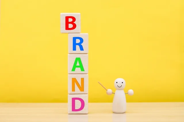 木製の人型模型が棒を持ち、 'BRAND' の文字を指しているイラスト。