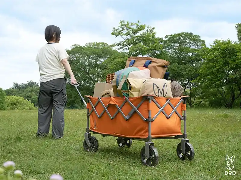 DODペリーワゴンにキャンプギアをたっぷり詰め込んで、女性キャンパーが引っ張って移動しているシーン。
