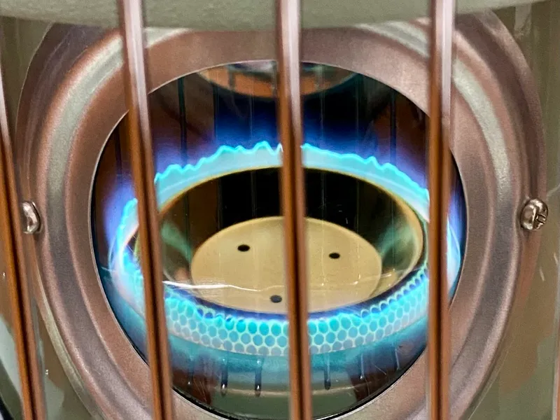 石油ストーブの窓から見える美しい炎。燃焼性が高く、安全に使える様子を表現した画像。