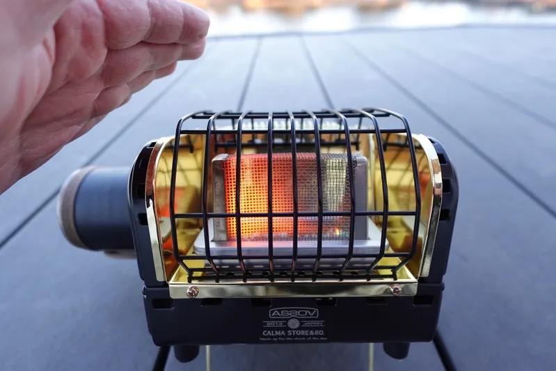 シャンクヒーター（AS2OV別注）を稼働させ、片手をかざして暖を取る使用シーンの実撮影写真