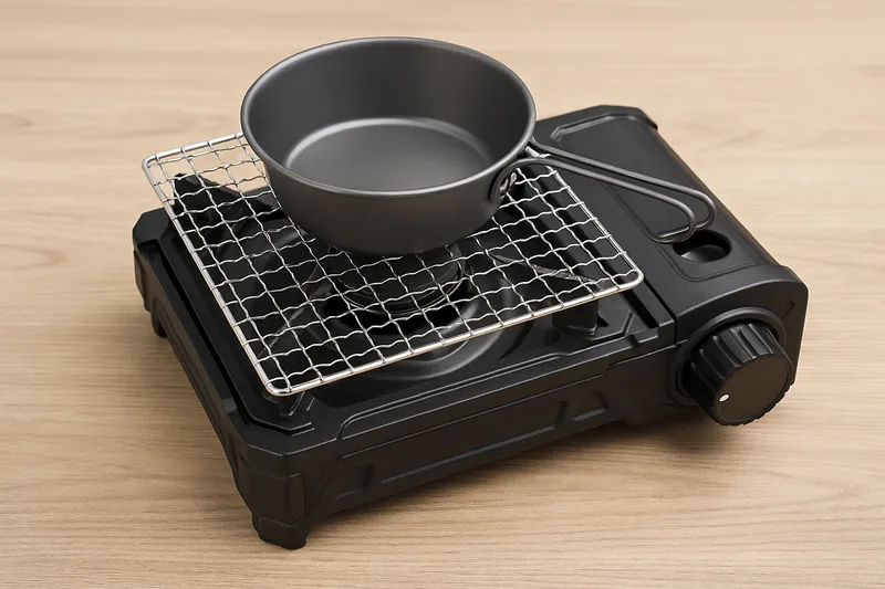 タフまる風カセットコンロにダイソーの焼き網(100均グッズ)を五徳に載せ、その上にシェラカップを置いている様子