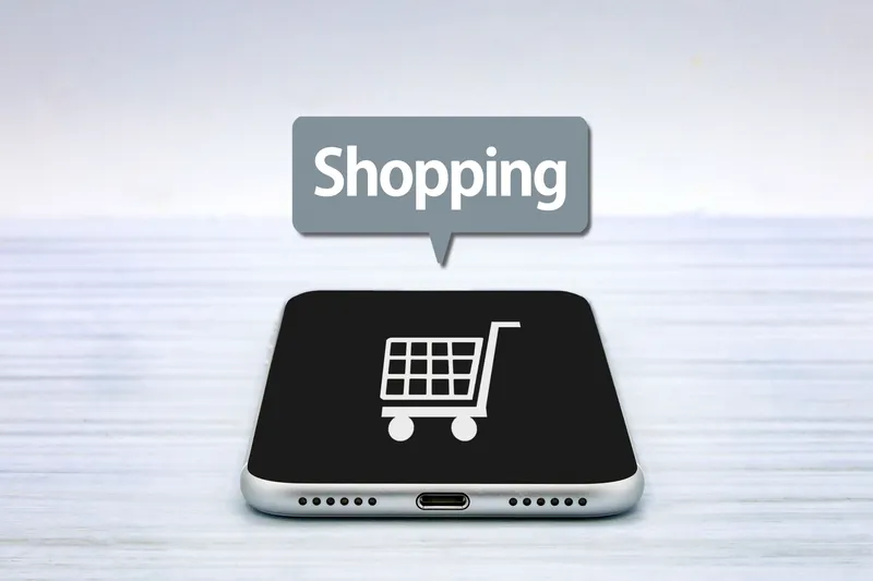 スマートフォン画面にカートアイコンと「Shopping」の文字が表示された、ネットショッピングをイメージしたイラスト。