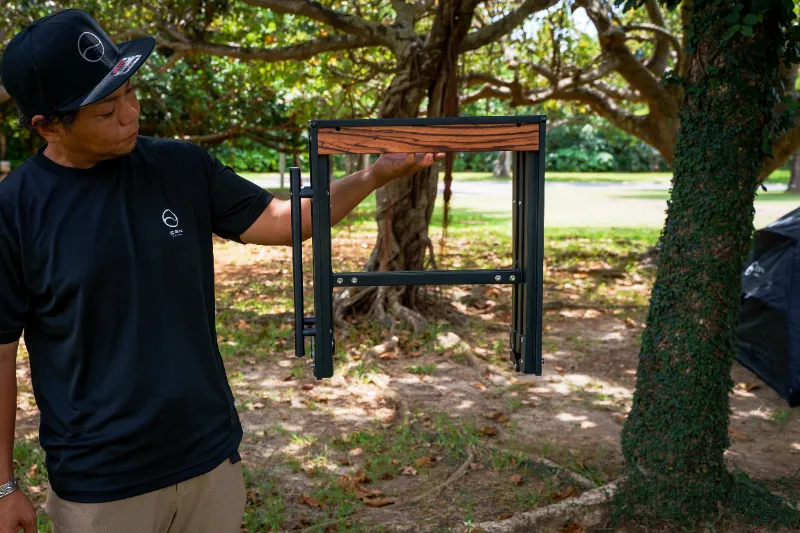 キャンプサイトでZENキャンプ(ZEN Camps)のIGTテーブル『FoldFlex Table』を折りたたんで半分サイズにしている様子