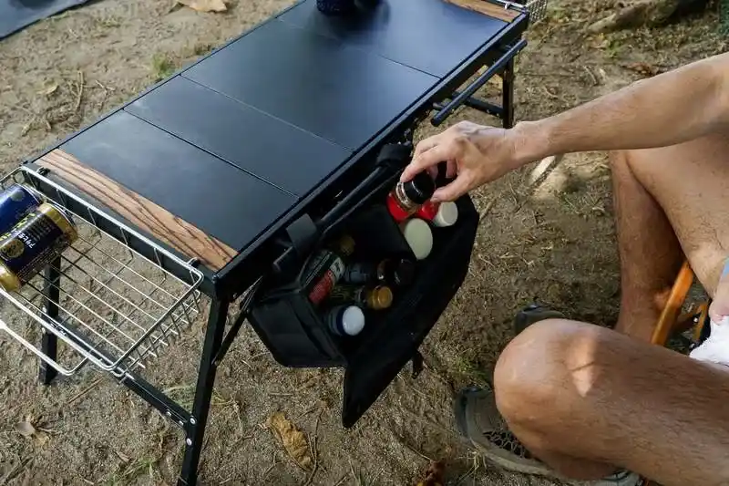 ZENキャンプ(ZEN Camps)の『FoldFlex Table』の前方ハンガーに調味料入れケースを取り付けて使用している様子